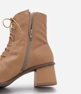 Bota de cuero color marrón claro, de caña media, con puntera cuadrada, taco bloque y cierre con cordones y cremallera.