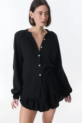 Camisa beige de manga larga con botones y detalles de encaje.