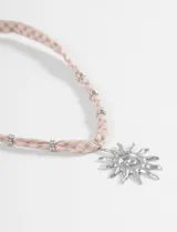Collar con cordón de tela rosa y verde a cuadros, adornado con cuentas metálicas plateadas. Incluye un dije grande de sol plateado con espiral central.