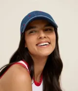 Gorra de béisbol de denim azul, con visera curva y bordados pequeños de corazones rojos.