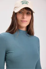 Blusa de punto canalé color verde azulado, de cuello alto y manga larga.