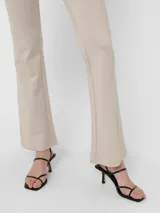 Pantalón tipo calza color beige, de corte flare y tiro alto.