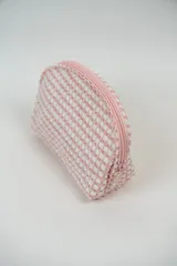 Neceser pequeño con textura de puntos en relieve color rosa y blanco, con cierre superior de cremallera rosa.
