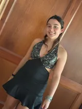 Vestido corto de lentejuelas color verde oliva, con escote en V, breteles finos cruzados en la espalda, cut-outs laterales y volado en el ruedo.