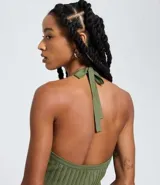 Vestido sin mangas de corte evasé, color verde oliva, con escote redondo y detalle de lazo en el cuello. El tejido presenta un efecto tricot texturizado acanalado.