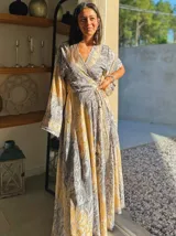 Kimono largo de seda con estampado floral en tonos verde, marrón y beige. Tiene mangas amplias y corte cruzado con lazo ajustable en la cintura.