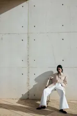 Camisa oversized de sarga color beige con rayas verticales marrones, cuello clásico, cierre frontal con botones ocultos, mangas largas con puños abotonados y bajo recto.