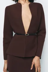 Chaqueta marrón de punto con cuello redondo y manga larga. Incluye cinturón fino negro con hebilla circular.