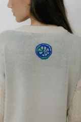 Buzo azul marino tejido en jacquard con diseño de frutas y verduras. Tiene mangas tejidas en ochos, bordado en la espalda y puños con agujerito para el dedo.