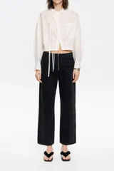 Pantalón denim negro de corte recto con largo tobillero, cierre frontal con cremallera metálica y bolsillos falsos con vivo.