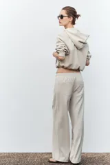 Pantalón de tiro alto color hueso, con bolsillos delanteros y traseros, cintura elástica ajustable con cordones y corte ancho.