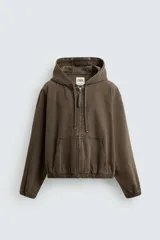 Cazadora marrón de algodón con capucha ajustable, corte relaxed fit, manga larga, bolsillos frontales tipo canguro, acabados con elástico y cierre frontal de cremallera.