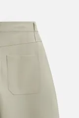 Pantalón negro de corte amplio tipo balloon fit, con cintura con pliegues frontales, bolsillos delanteros y traseros de plastrón. Cierre frontal con cremallera y botón.
