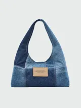 Bolso tipo hobo Marc Jacobs The Sack Bag, confeccionado en tela de patchwork de denim en tonos grises y negros. Presenta el logo estampado en blanco en el lateral.