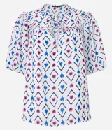 Blusa de chiffon con estampado geométrico en tonos blanco, azul y rosa. Tiene cuello redondo con lazo, mangas cortas abullonadas y volados en el cuello y los puños.