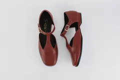 Zapato flat color ladrillo, con corte en forma de T y hebilla lateral.