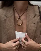 Collar con dije circular irregular de alpaca y plata 925, con hilo de algodón natural.