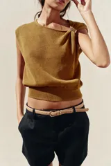 Top dorado de tejido de punto con cuello barco, sin mangas y detalle de fornitura metálica en el hombro.