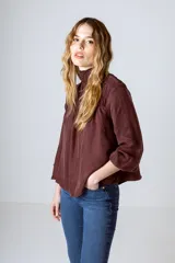 Blusa negra con cuello alto fruncido y mangas largas abullonadas con puños elásticos.