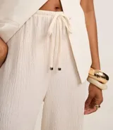 Pantalón wide leg color beige con textura, cintura elástica con cordón ajustable y bolsillos laterales.
