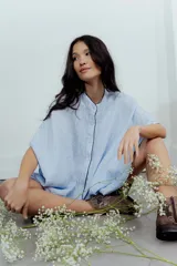 Camisa celeste de lino con corte amplio, cuello mao y mangas cortas. Presenta cierre frontal con botones y ribete negro en cuello y tapeta.