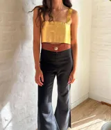 Top corto dorado con breteles anchos y escote recto con detalle de volados.