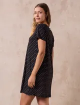 Camisón corto negro con lunares blancos, de tejido suave y escote redondo con detalle plisado y moño blanco.