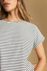 Remera de manga corta con cuello redondo, confeccionada en tejido acanalado a rayas horizontales blancas y negras.