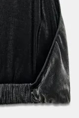 Top negro brillante con cuello halter ajustable con botones a presión, hombros descubiertos, detalle de tira elástica cruzada en la espalda y bajo abullonado.