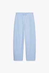 Pantalón tipo barrel con rayas verticales celestes y blancas, tiro medio y cintura elástica ajustable con lazo. Tiene bolsillos laterales y falsos bolsillos de vivo en la espalda.