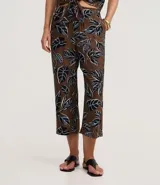 Pantalón tipo pantacourt de calce holgado y tiro alto, confeccionado en tejido de viscosa con estampa de follaje en tonos negro, blanco y azul sobre fondo marrón. Posee cintura elástica.