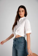 Camisa corta negra con detalles de encaje, de mangas cortas y anudada en la parte delantera.