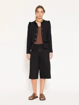 Chaqueta corta de jacquard chanel color celeste, con cuello redondo y cierre frontal con botones marrones. Presenta detalles de flecos en el escote, bolsillos delanteros inferiores y sisas.