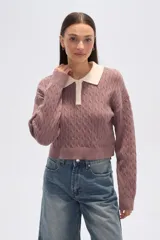 Sweater de tejido de punto con trenzas, color malva/rosado, de corte cropped y manga larga. Presenta cuello polo con solapas en color crema y cierre frontal de botones.