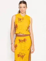 Musculosa amarilla estampada con diseño exclusivo JCH, con tiras laterales en tela color chocolate que enmarcan una abertura en los laterales, sostenida por lazos del mismo material.