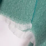 Ruana color verde agua con textura de espiga, cuello en V, un bolsillo frontal y flecos blancos en el borde inferior.