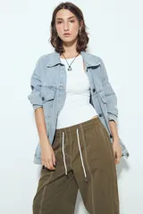 Pantalón tipo babucha negro de tiro bajo con costuras visibles en contraste blanco. Presenta cintura elástica con lazo ajustable blanco y silueta amplia con caída relajada.