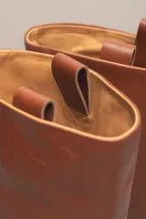 Bota alta de cuero color marrón, con caña recta y suela plana.