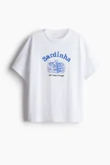Remera blanca de corte amplio, con cuello redondo y estampado azul de una lata de sardinas con la palabra 'Sardinha' y la frase 'São Vicente, Portugal'.