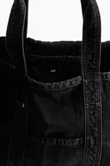 Bolso shopper grande de denim negro con efecto lavado. Tiene dos asas cortas, un bolsillo exterior abierto y un compartimento interior pequeño.