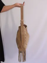 Bolso tipo bandolera de cuero negro con flecos y tachas plateadas. Tiene correa regulable, forro interior y bolsillo interno.