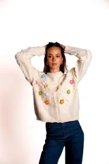 Saco de punto color rojo, con cuello polo y cierre frontal de botones blancos. Presenta flores bordadas en relieve de diferentes colores (azul, amarillo, verde, naranja, rosado) y mangas largas con diseño de burbujas.