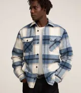 Campera trucker masculina de terciopelo a cuadros en tonos azul, blanco y beige. Tiene cuello inglés, cierre abotonado, bolsillos delanteros y laterales.