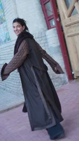 Abrigo largo marrón con mangas de cuero acolchado, cuello de piel sintética y cinturón de cuero.