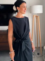 Vestido largo sin mangas de color negro, confeccionado en tejido de tencel. Presenta un diseño de cuello redondo y un lazo frontal anudado en la cintura que crea un efecto drapeado.