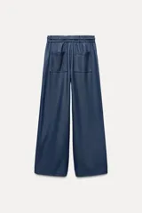 Pantalón de tiro alto azul denim, con cintura elástica ajustable con cordón, bolsillos laterales y traseros, y pernera ancha.