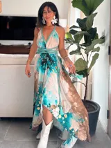 Vestido largo de tela fluida, color verde esmeralda con estampado abstracto en tonos turquesa y detalles dorados. Diseño asimétrico con un solo tirante tejido en el hombro.