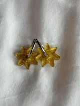 Par de aros dorados con forma de estrella negra.