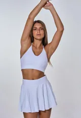 Conjunto deportivo blanco compuesto por top con breteles finos y falda corta tableada.