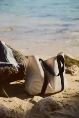 Bolso de playa de lona color crudo con asas de cinta negra.